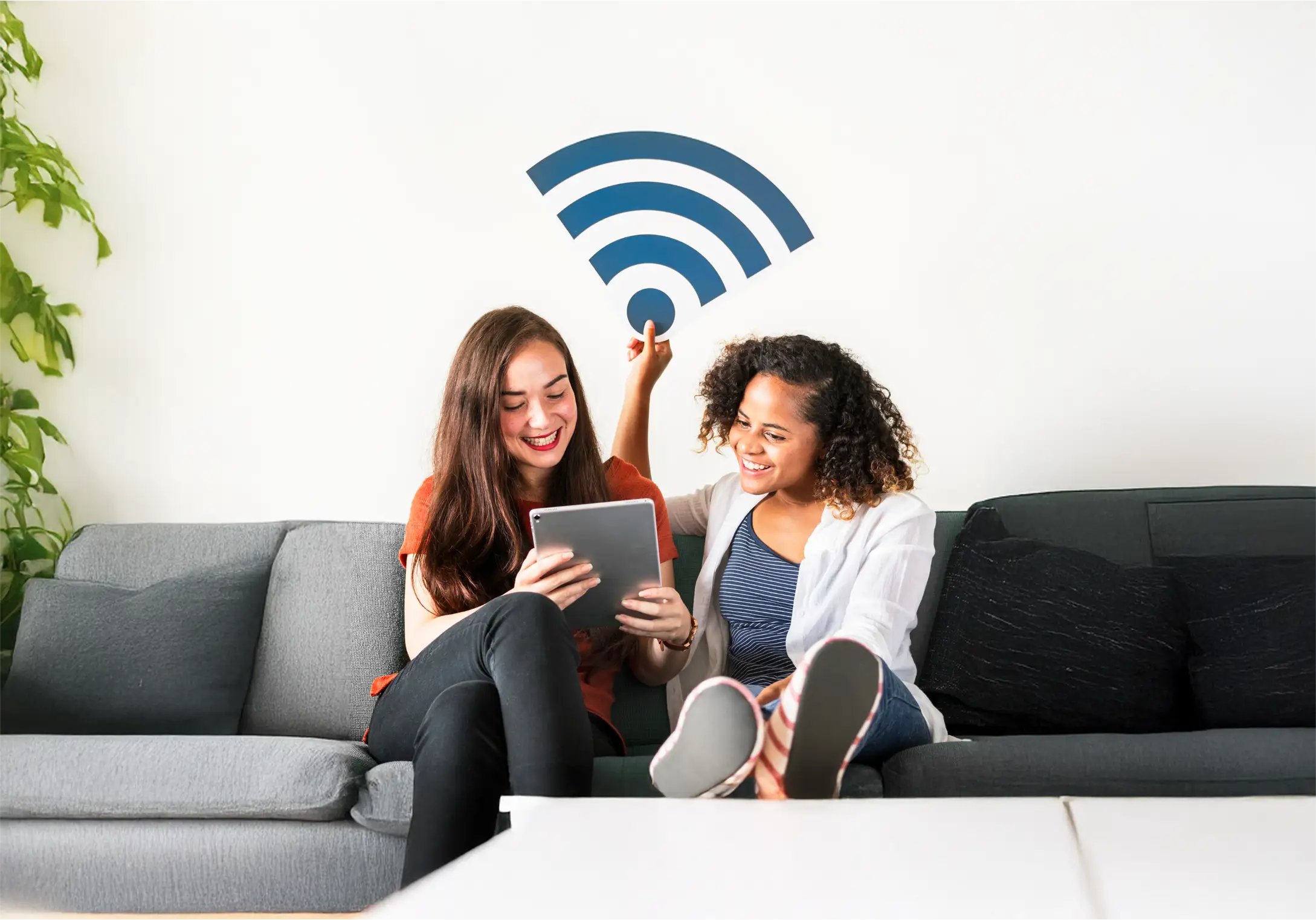 Two women enjoying a tablet on a sofa.