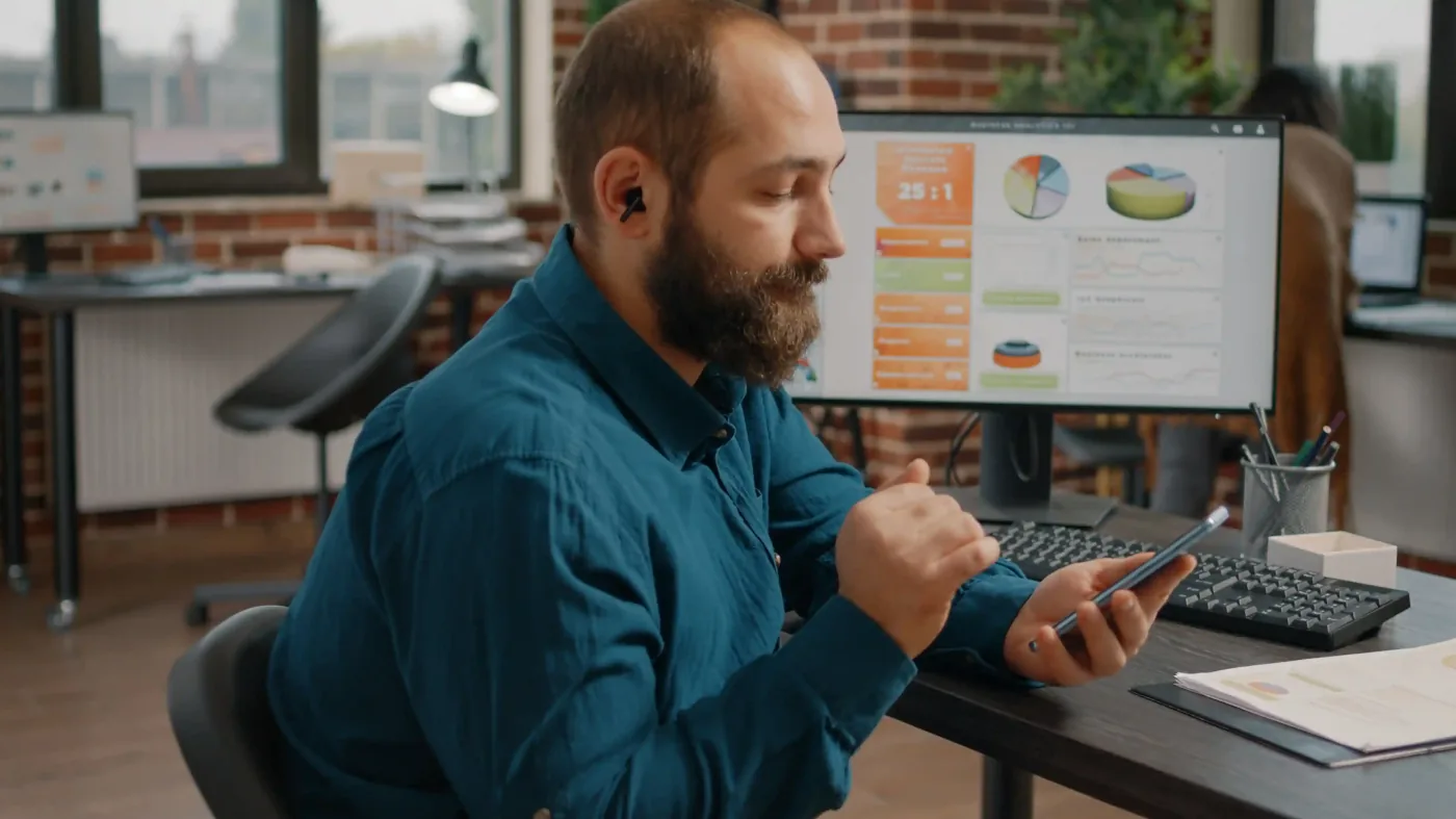 Man using smartphone at a desk in office