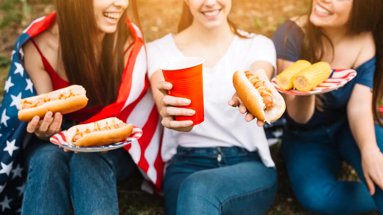 Friends enjoying hot dogs and corn outdoors