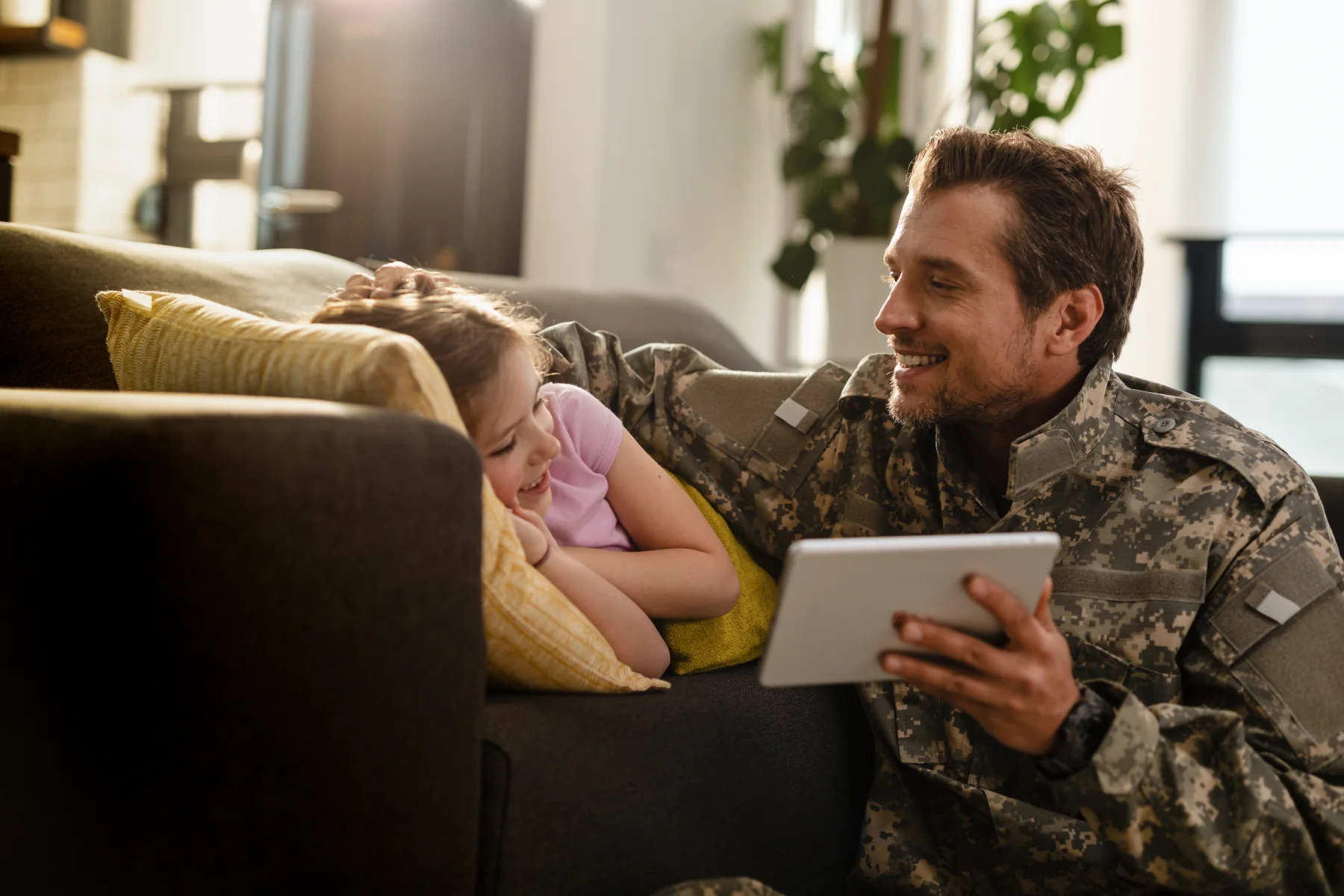 Smiling soldier and girl enjoying tablet together.