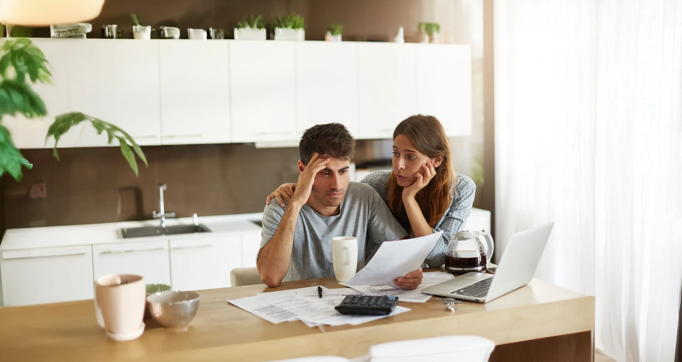 Concerned couple reviewing documents at kitchen table.