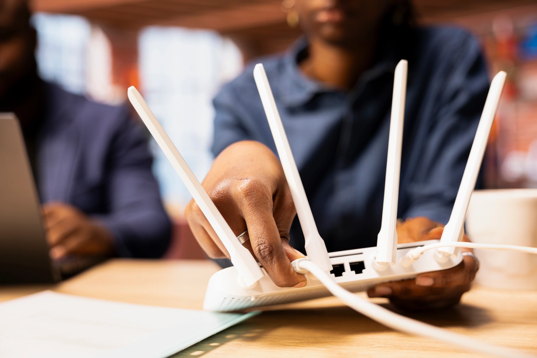 Person connecting a router on a desk.