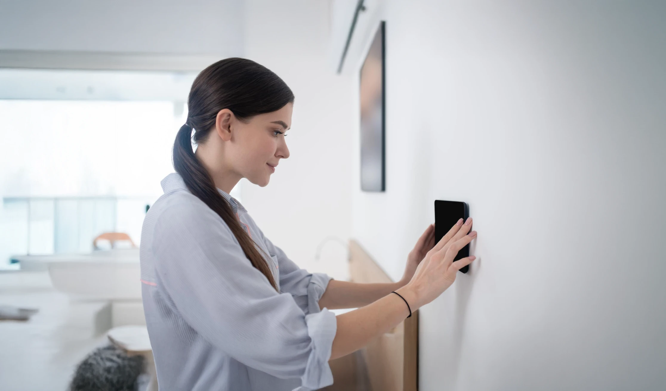 Woman adjusting a smart home device on wall.